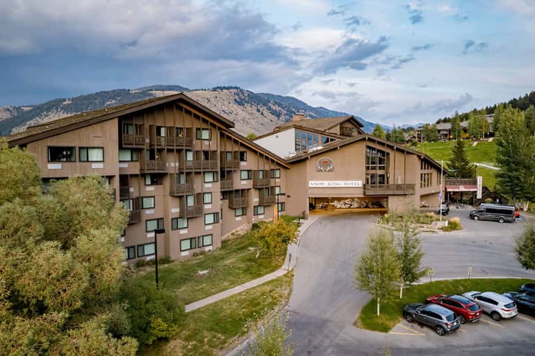 Snow King Hotel mountain lodge with timber architecture, mountains, trees, and parking area