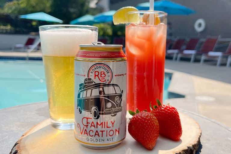 Poolside beverages including beer, cocktails, and fresh strawberries on wooden tray