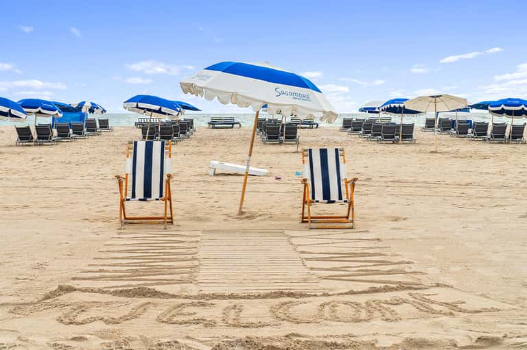 Beach chairs and umbrellas on sandy beach with striped loungers and blue parasols