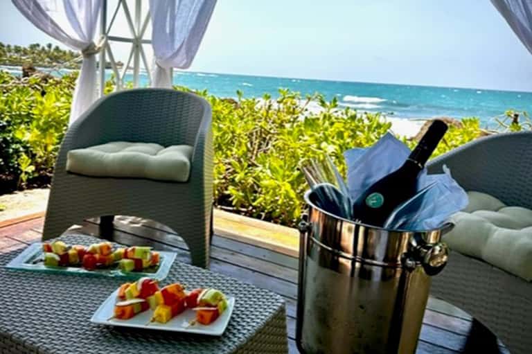 Oceanfront cabana with wine bucket, fruit skewers, and ocean view through sheer curtains