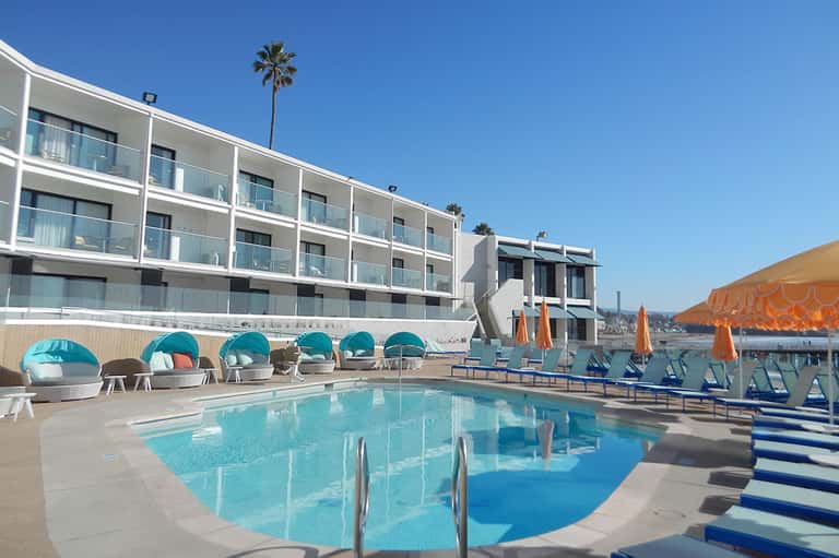 Contemporary hotel pool with turquoise water, modern buildings, and cabana seating
