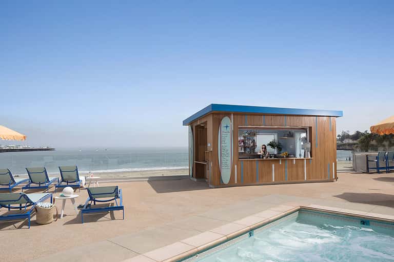 Beach bar kiosk with blue roof overlooking ocean and resort pool deck