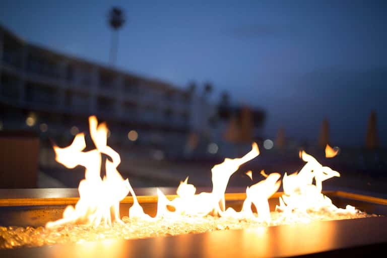 Evening fire pit with flames glowing against twilight sky and resort buildings in background