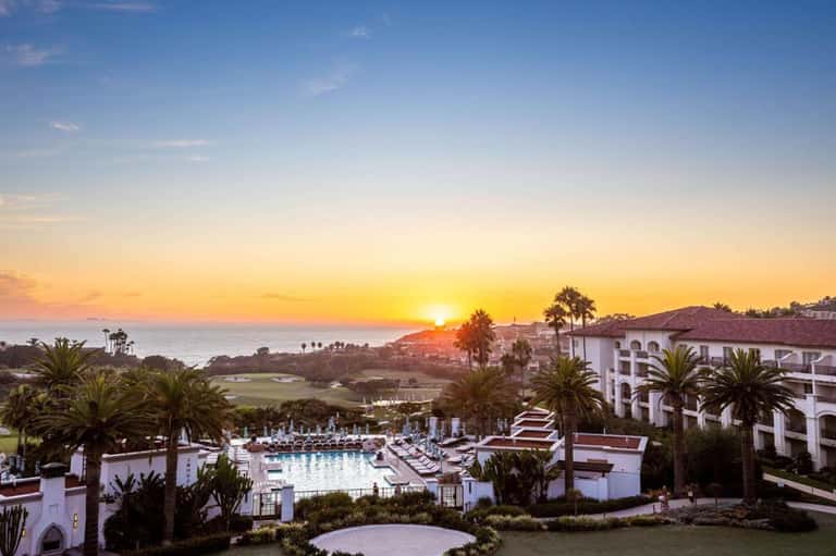 Coastal resort at sunset with pool, white buildings, and ocean horizon