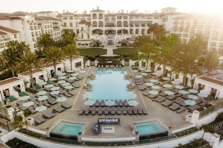 Grand resort courtyard pool surrounded by Mediterranean-style buildings and palm-lined grounds
