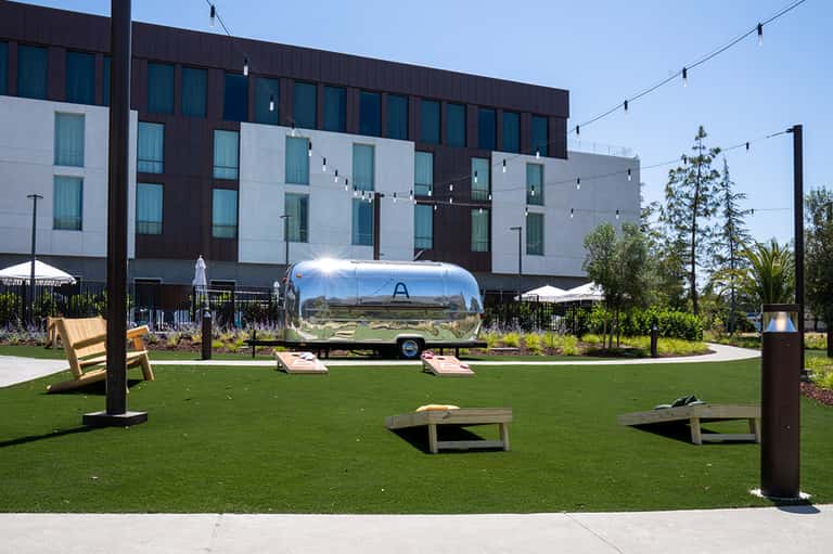Modern hotel courtyard with Airstream trailer, games, and contemporary architecture