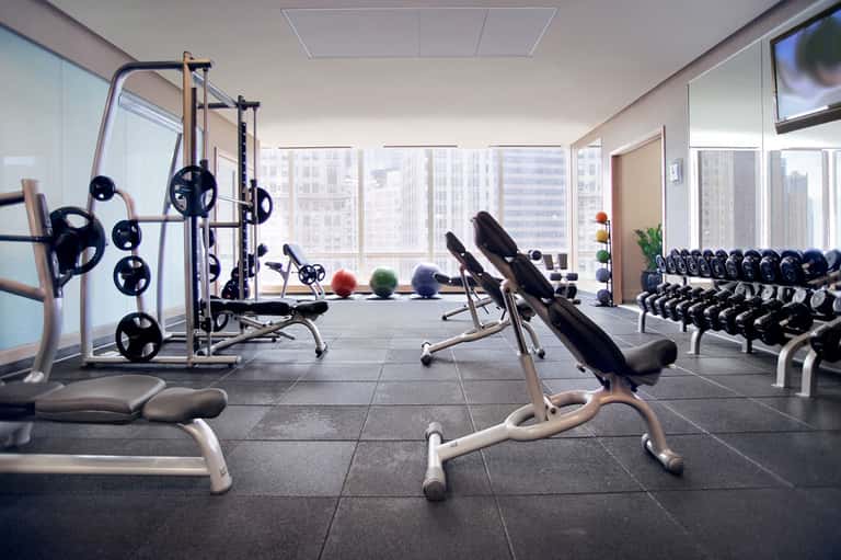 High-rise hotel fitness center with gym equipment, dumbbells, exercise machines, and city views