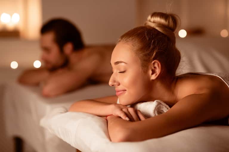 Spa massage treatment scene with candles, relaxed guest, and serene ambiance