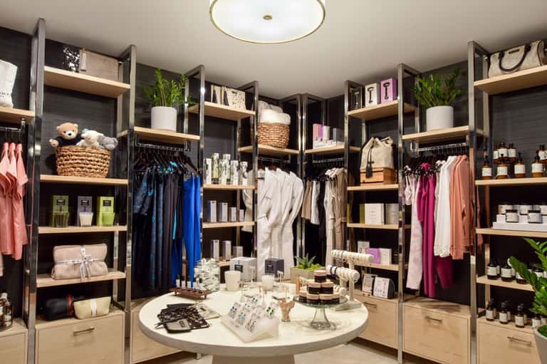 Upscale retail boutique interior with wooden shelving, clothing racks, and circular display table