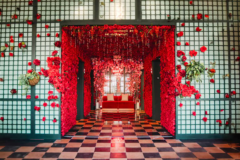 Elaborate red floral tunnel entrance with checkered floor and red velvet seating