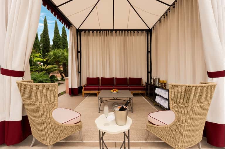 Luxury spa cabana with burgundy seating and cream curtains
