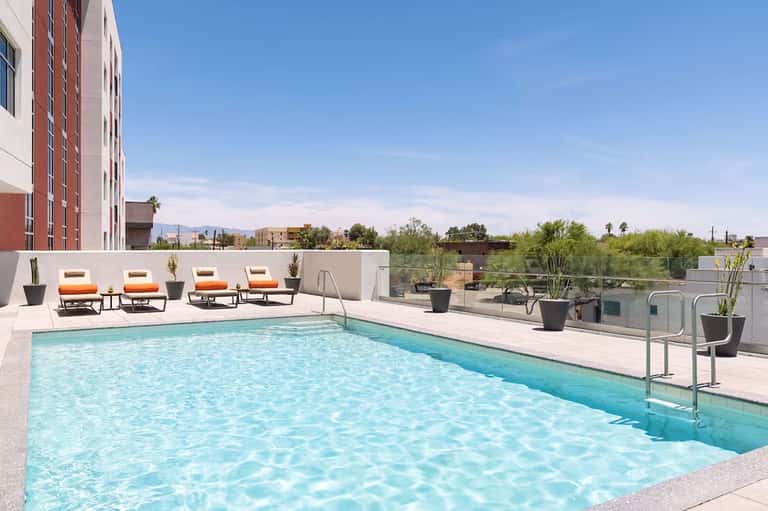 Rooftop pool deck with lounge chairs, mountain views, and desert landscape surroundings