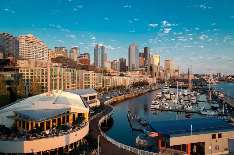 Waterfront cityscape showing marina, downtown skyline, and waterfront promenade at golden hour