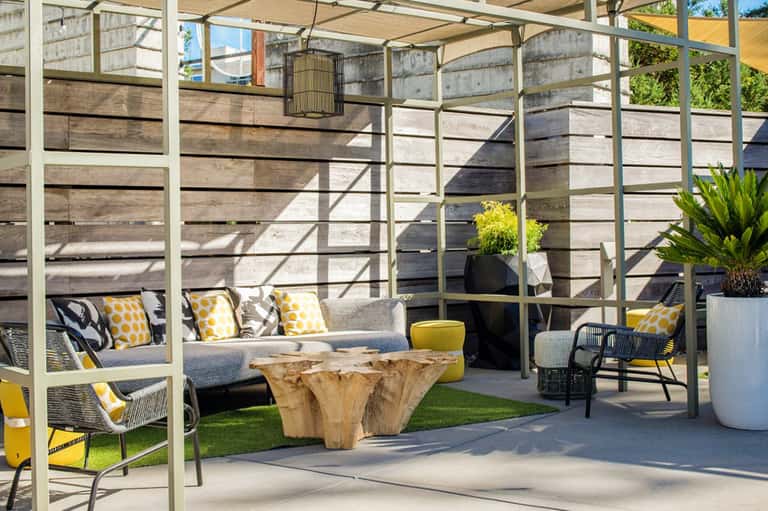 Contemporary outdoor terrace with pergola, gray seating, wooden table, and potted plants