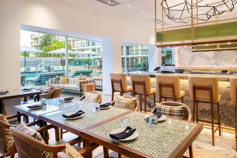 Contemporary restaurant dining area with tables, bar seating, and terrace overlooking urban landscape