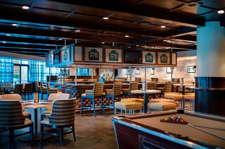 Modern pub interior with blue and tan color scheme, pool table, bar counter, and casual lounge seating
