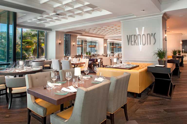 Upscale restaurant interior with modern furnishings, ocean view windows, and Vernon's signage