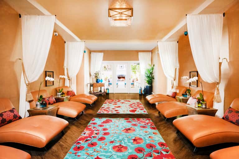 Luxurious spa relaxation room with orange leather loungers, white curtains, and ambient lighting