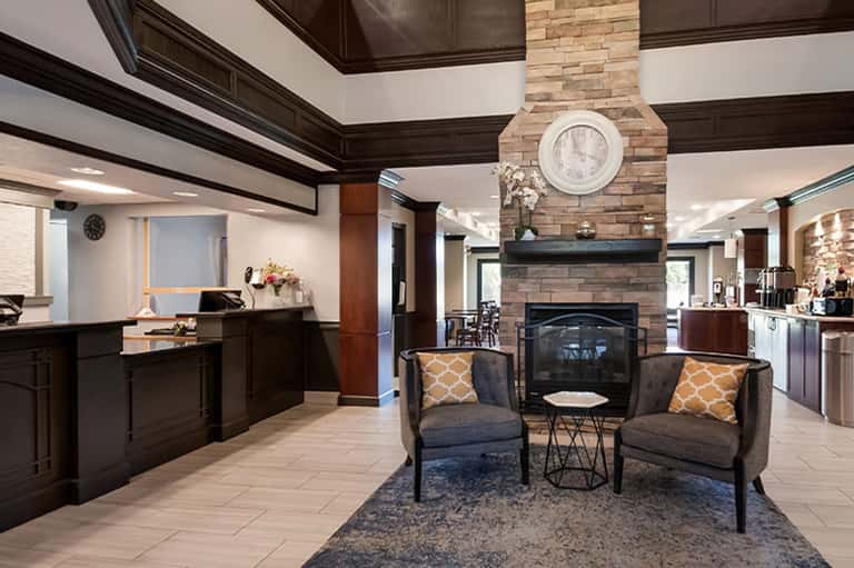 Modern hotel lobby with brick fireplace, dark wood, and seating area