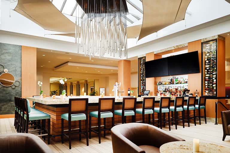 Modern resort bar with orange walls, chandelier, and full liquor selection
