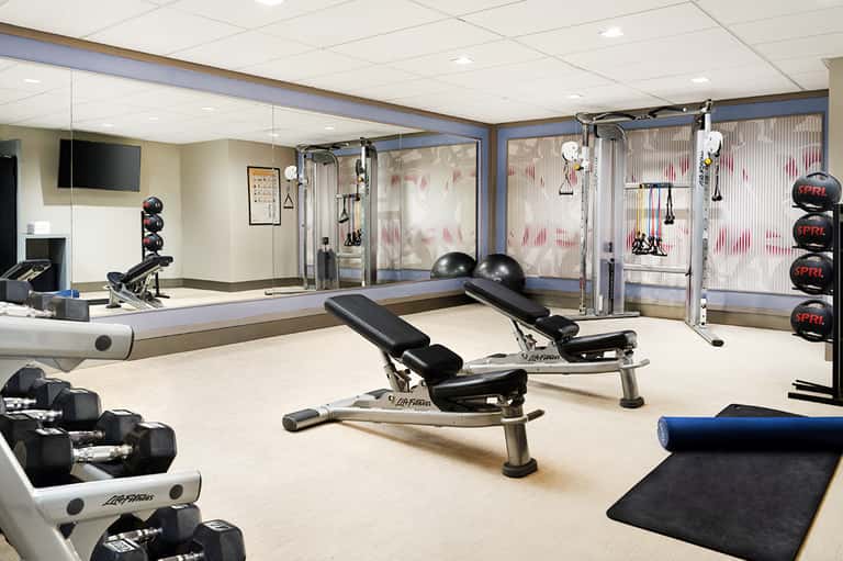 Modern fitness center with exercise equipment, mirrored walls, dumbbells, and workout machines