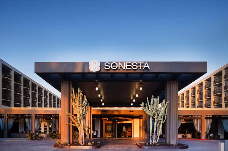 Sonesta hotel entrance with modern canopy, warm lighting, desert landscaping at dusk
