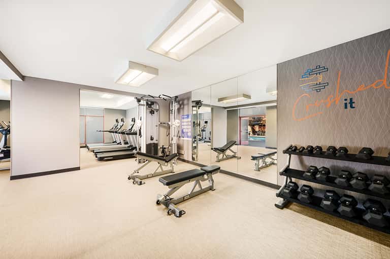 Fitness center with treadmills, weight equipment, mirrors, and motivational wall signage