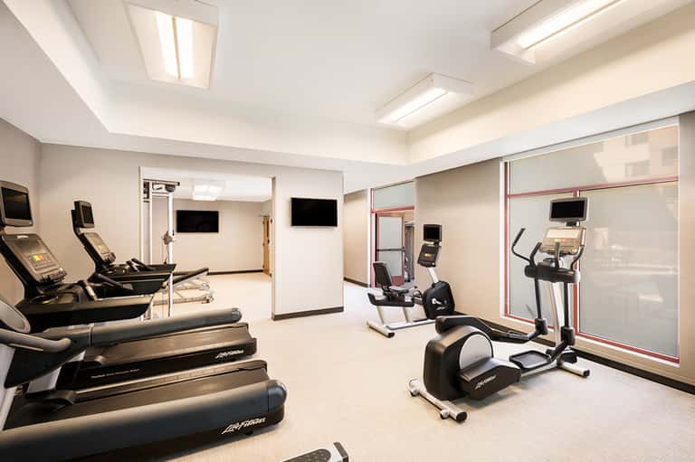 Modern hotel fitness center with treadmills, exercise bikes, and wall-mounted screens