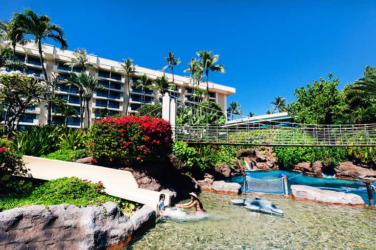 Resort building with balconies overlooking lagoon with water features and palm landscaping