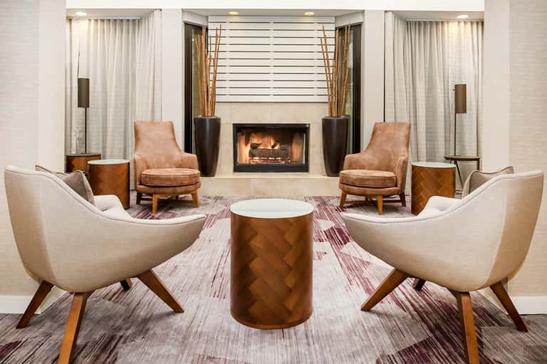 Elegant hotel lobby lounge with fireplace, cream and tan upholstered chairs, and sophisticated décor