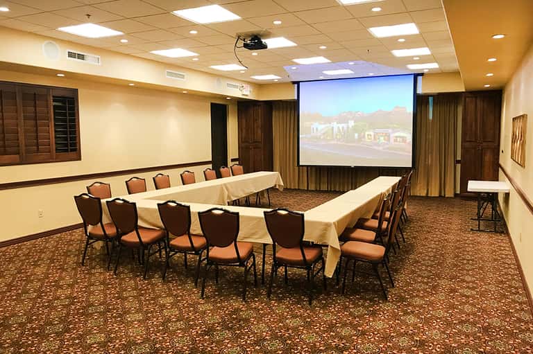 Conference room with U-shaped table setup, projection screen, and warm lighting