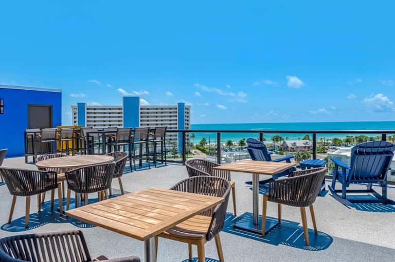 Rooftop terrace with modern furniture, ocean and coastline views, bright blue sky and turquoise water