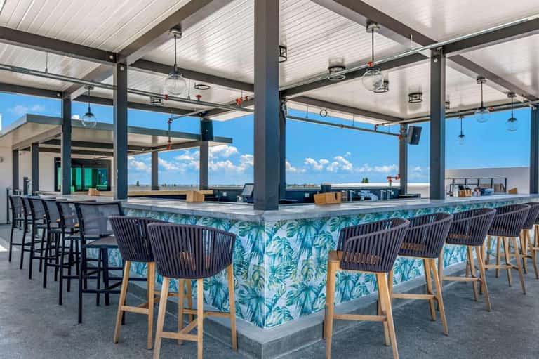 Rooftop bar with panoramic water views, pendant lighting, tropical bar design, and open air