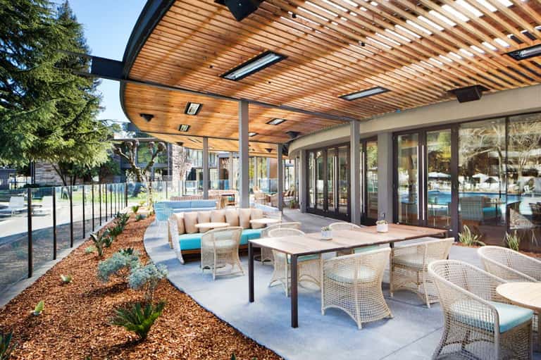 Contemporary patio area with wooden pergola, dining tables, lounge seating, and pool view