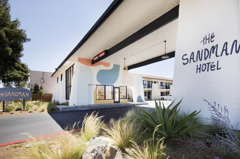 The Sandman Hotel exterior with modern white and beige architecture and desert landscaping