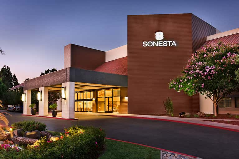 Modern resort building exterior with brick facade and SONESTA signage at dusk
