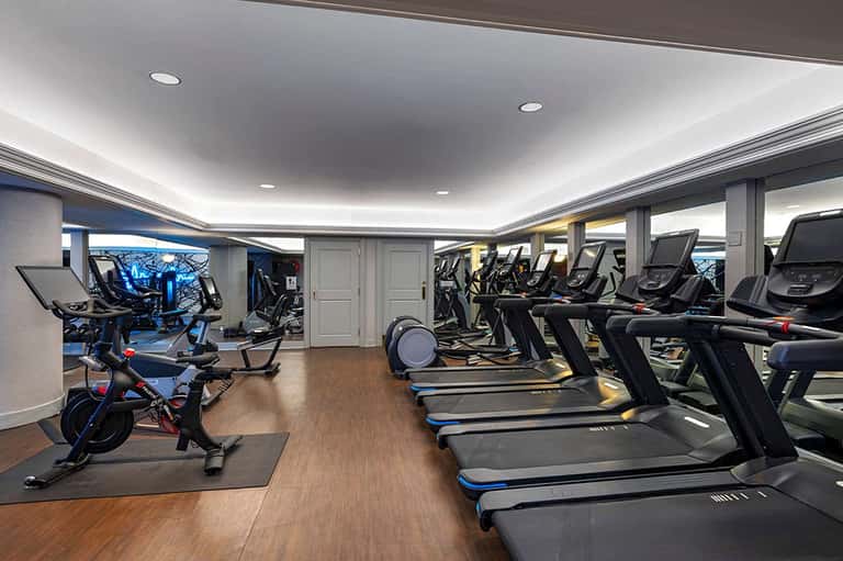 Modern fitness center with treadmills, stationary bikes, and recessed ceiling lighting