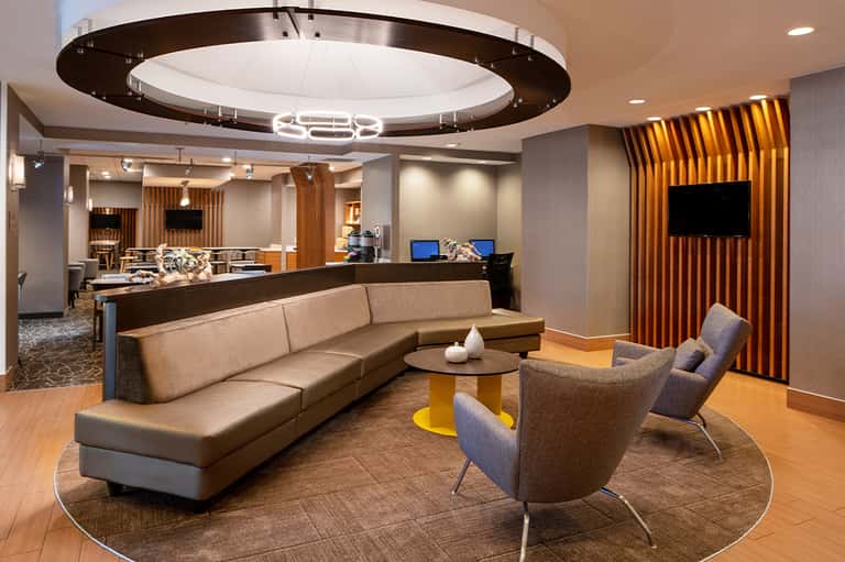 Modern hotel lobby lounge with circular ceiling light and tan seating