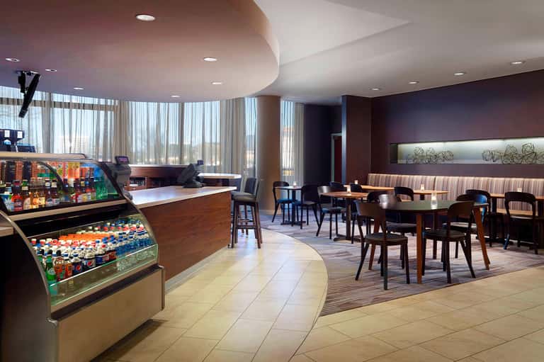 Hotel lounge with snack bar, seating area, large windows, and modern furnishings
