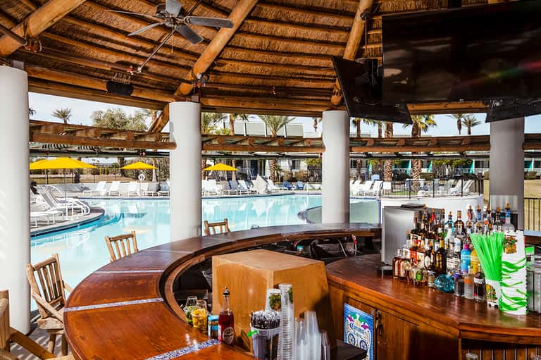 Pool bar with wooden beams, lounge chairs, and tropical resort setting