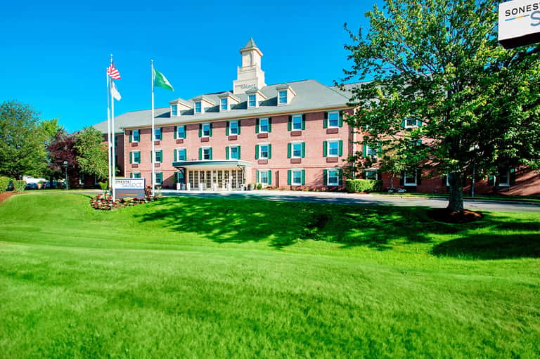 Historic red brick hotel building with manicured lawn and clear blue sky