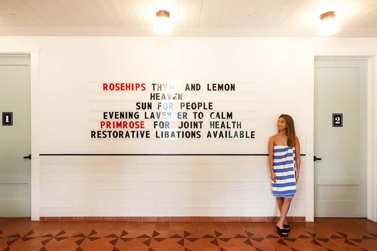Woman in striped dress beside wellness-themed text wall at spa entrance