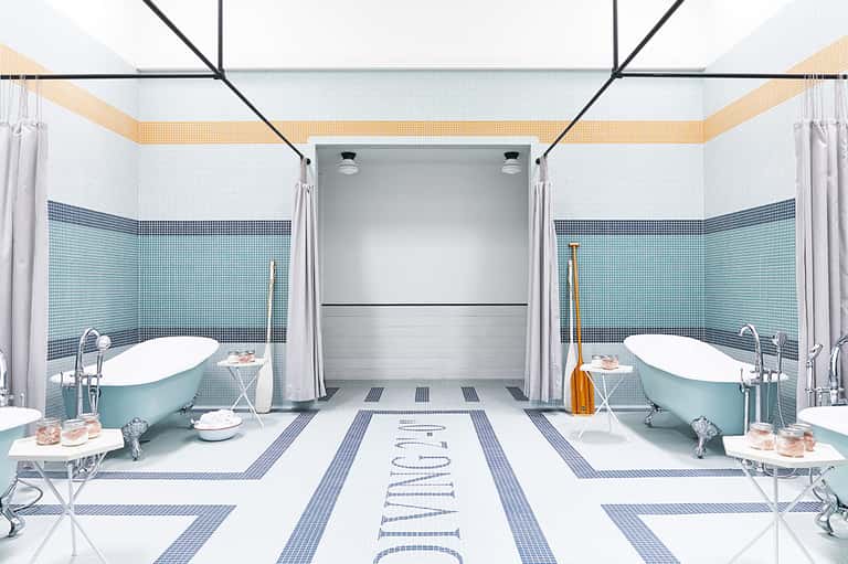 Elegant dual bathroom with turquoise bathtubs, blue tile walls, and marble flooring