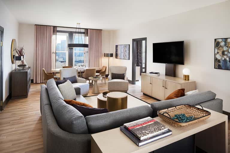 Luxury hotel suite with curved sofa, ocean view, modern furnishings and pink curtains