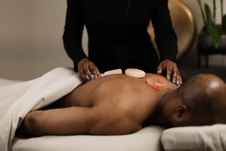 Spa treatment showing therapist performing hot stone massage on client's back