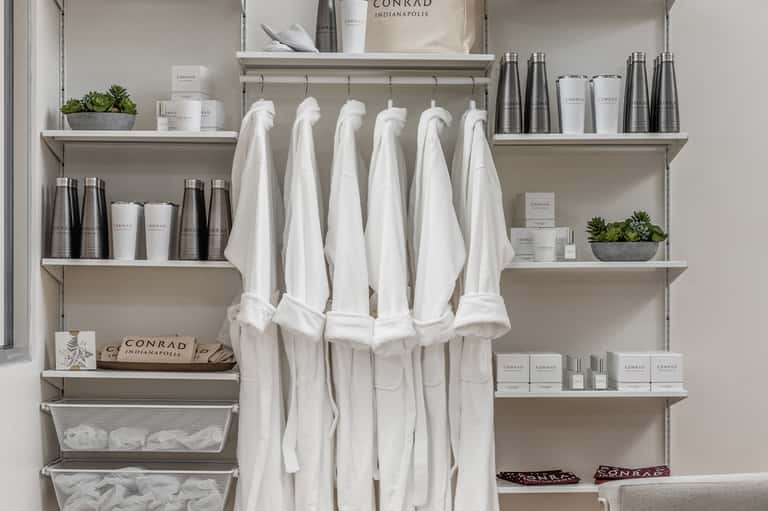 Spa amenities shelf display with white towels, Conrad branded products, and potted succulents