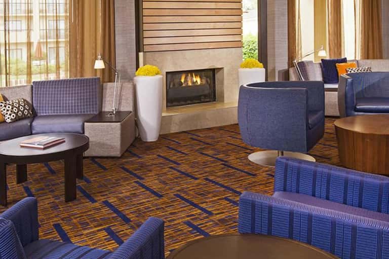 Hotel lobby lounge with fireplace, blue seating, pendant lighting, and modern furnishings