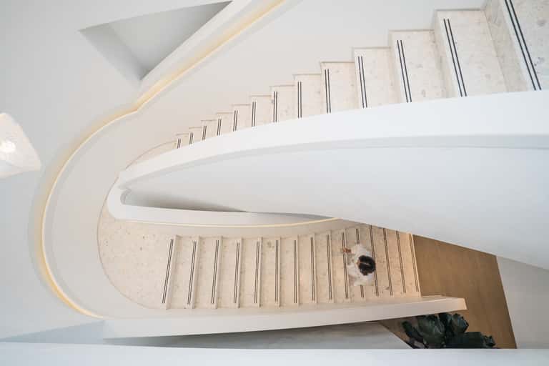 Modern spiral staircase with white walls, light wood steps, and contemporary architectural design