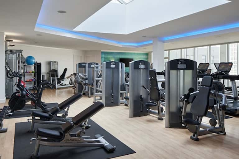 Modern fitness center with cardio equipment, strength machines, and blue accent lighting in ceiling