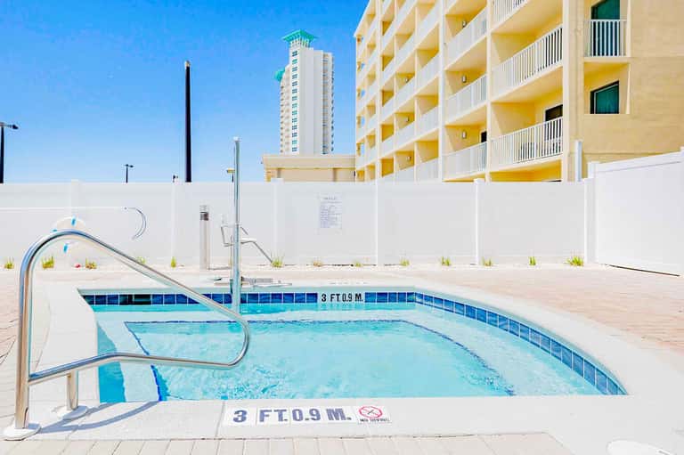 Rectangular pool with blue water and metal railings in front of yellow apartment building